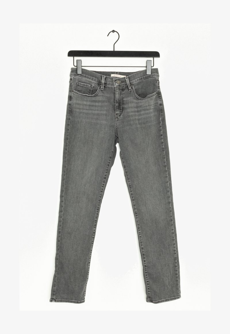 Jean slim gris avec poches avant et passants de ceinture suspendu sur un cintre noir contre un fond blanc.