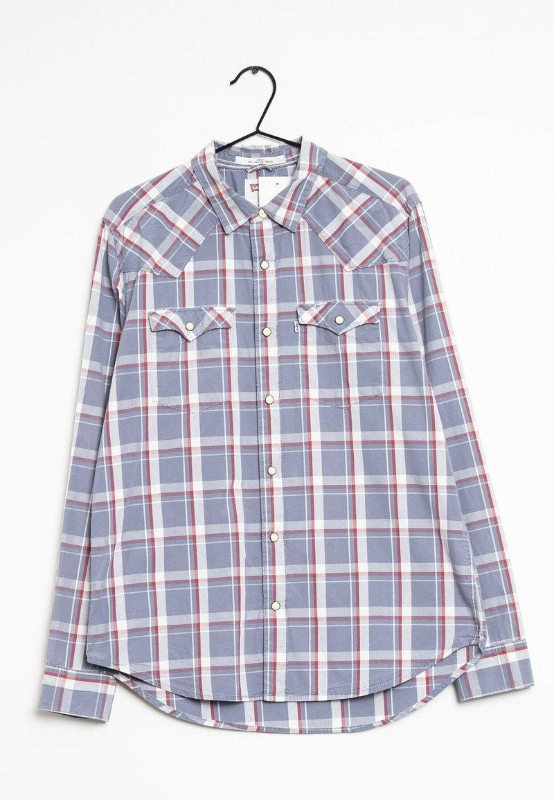 Chemise à manches longues à carreaux bleu, blanc et rouge avec deux poches poitrine, présentée sur un cintre noir sur un fond blanc.