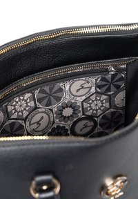 Sort lædertaske indeni med et geometrisk mønster i grå nuancer, med en lynlåslomme og guld lynlåsvagter.