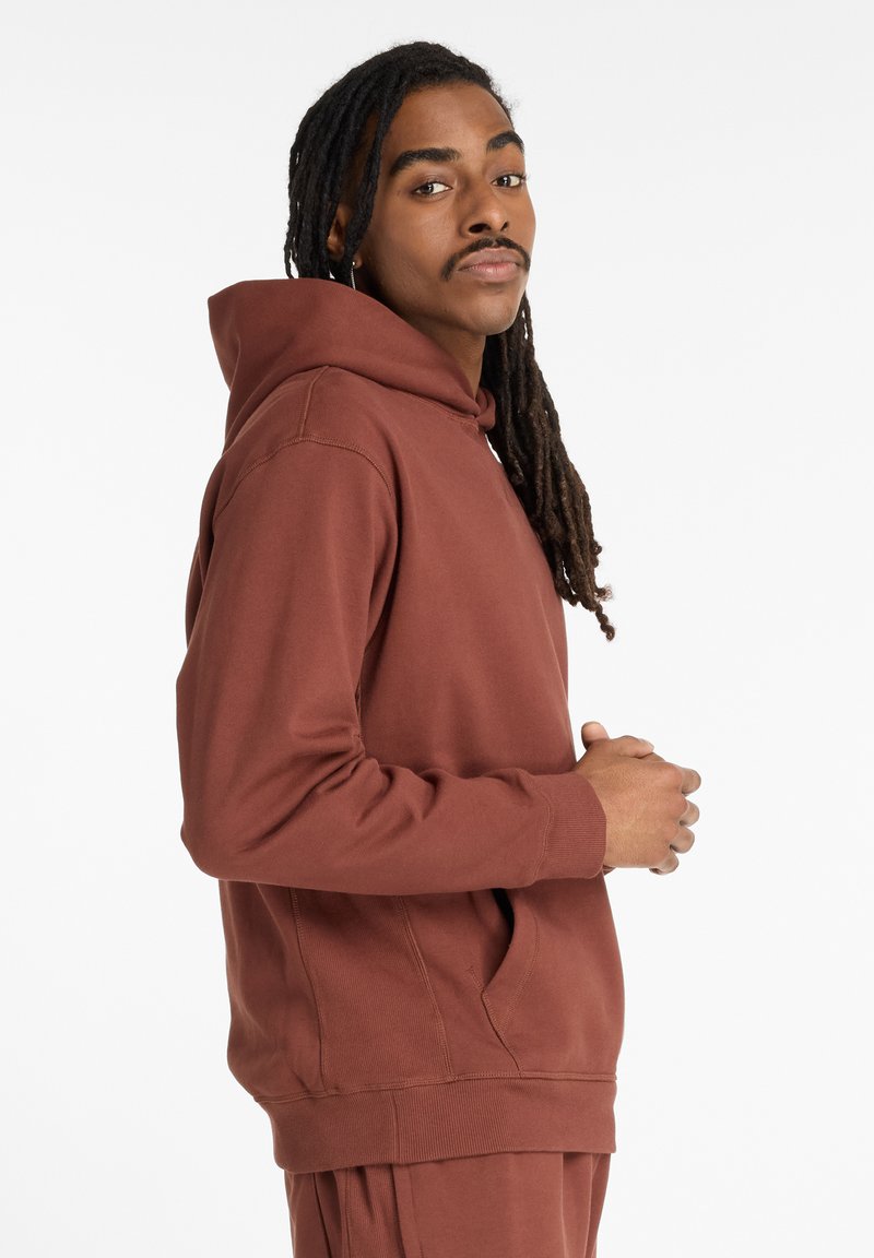 Brown hoodie made of soft fabric, featuring a drawstring hood, kangaroo pocket, ribbed cuffs, and hem. Simple design with a relaxed fit.