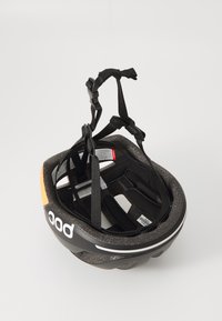 Cappellino da bici nero con finitura opaca testurizzata, cinghie nere regolabili e un accento arancione. Presenta fessure di ventilazione per il passaggio dell'aria.