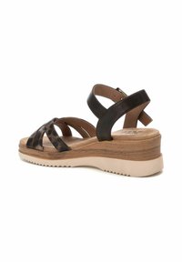 Sandalias de cuero negro con cintas cruzadas, suela estilo madera y fondo de goma beige claro. Correa trasera para un ajuste seguro.