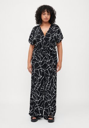 Combinaison noire avec un motif abstrait blanc audacieux, manches courtes, décolleté en V, taille cintrée et pantalons larges. Tissu texturé.