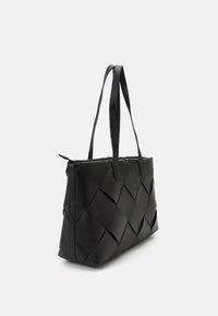Svart vävd tote-väska med platta handtag, med en strukturerad form och texturerat mönster. Tillverkad av syntetiskt material med dragkedjestängning.