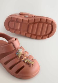 Pink rubber sandals with a closed toe design and three cutouts, featuring colorful animal embellishments on the front. Textured sole for grip.