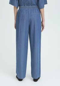 Blauwe denim wijde broek met een elastische tailleband, met twee achterzakken en een taps toelopende zoom. Gladde textuur en casual ontwerp.