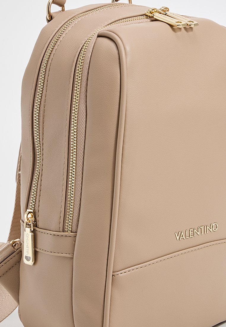 Zaino beige Valentino con cerniere e logo dorati, dotato di due scomparti con zip e spallacci regolabili.
