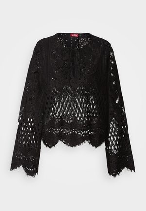 Melna mežģīņu blūze ar sarežģītu izgriezumu rakstu, viļņotām malām, garām piedurknēm un mežģīņu detaļu apkaklē. Mīksta tekstūra.