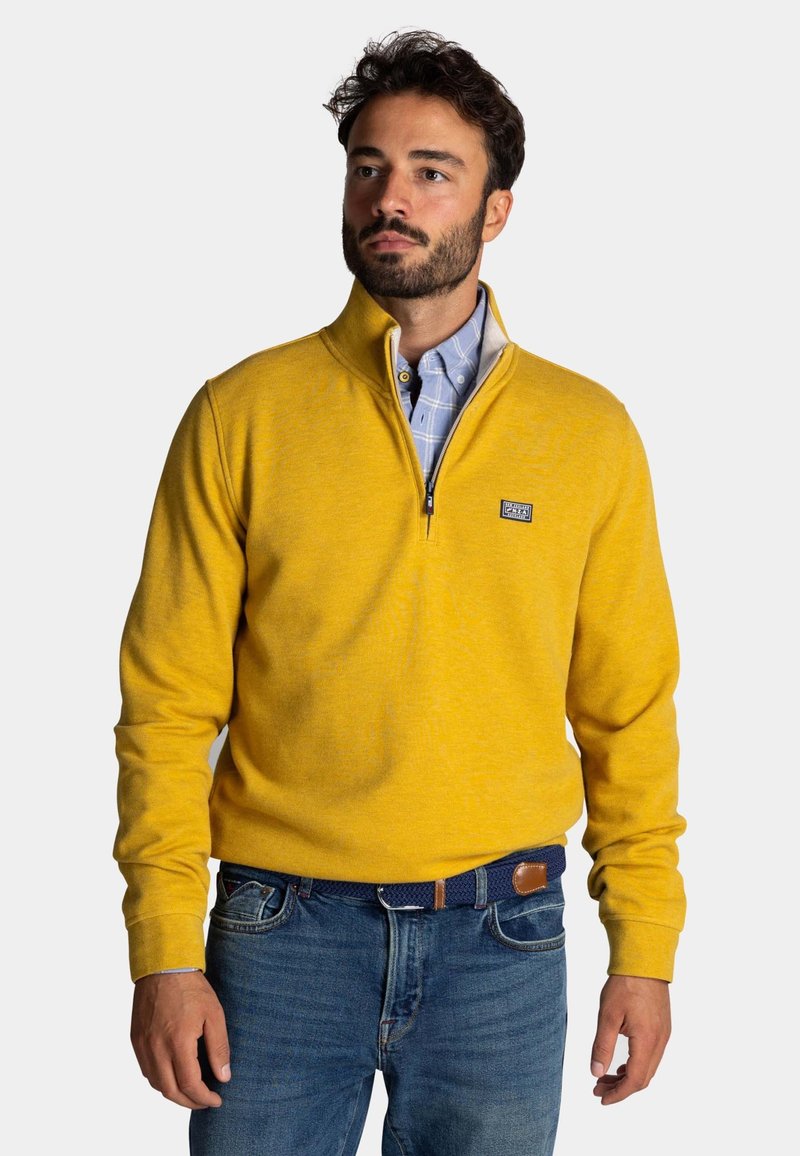 Geel fleece sweatshirt met een half-rits kraag, zachte textuur en logo patch; gelaagd over een lichtblauw geruit overhemd. Casual fit.