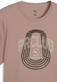 T-shirt de sport rose clair en tissu respirant, doté d'un col rond, d'une surface texturée et d'un logo graphique avec le texte "PUMA RUN CLUB".