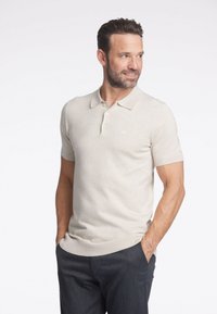 Beige kortärmad polo skjorta i mjukt stickat tyg, med klassisk krage och treknappslå, samt diskret logotypdetalj på bröstet.