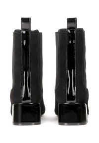 Botas negras de tobillo con un acabado de ante texturizado, acentos de charol brillante y un tacón grueso y brillante. Cuenta con una pestaña de agarre en la parte posterior.