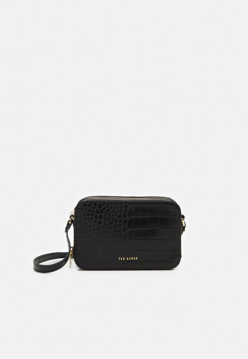 Sac à bandoulière en faux cuir noir avec texture crocodile, fermeture éclair, accents en hardware doré et une bandoulière amovible. Marque Ted Baker en doré.