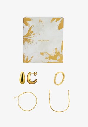 Das goldene Schmuckset umfasst zwei Paar Ohrringe, ein Armband und eine gedrehte Halskette. Die Verpackung zeigt ein florales Design in Gold und Weiß.