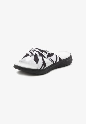 Black and white striped slide sandal with crisscross straps, rubber sole, and textured footbed. Features a metal accent on the strap.