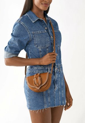 Sac en cuir brun en bandoulière avec une forme arrondie, des coutures décoratives et un détail de boucle. Doté d'une longue sangle pour un port sur l'épaule.