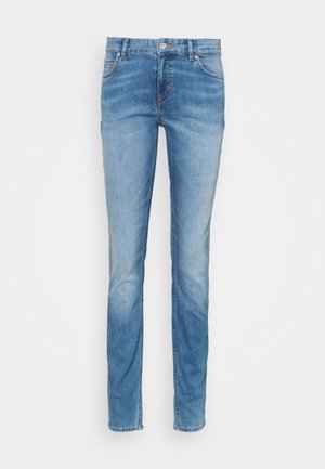 Vaqueros de denim de color azul claro, con un corte recto clásico, cinco bolsillos y un cierre de botón en la cintura. Áreas desgastadas para dar textura.