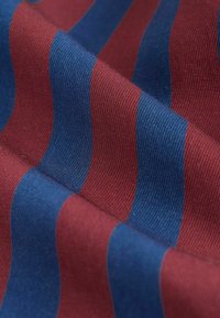 Tissu tissé présentant des rayures rouges et bleues alternées. La texture est nervurée, montrant de la profondeur et de la dimension dans le motif.