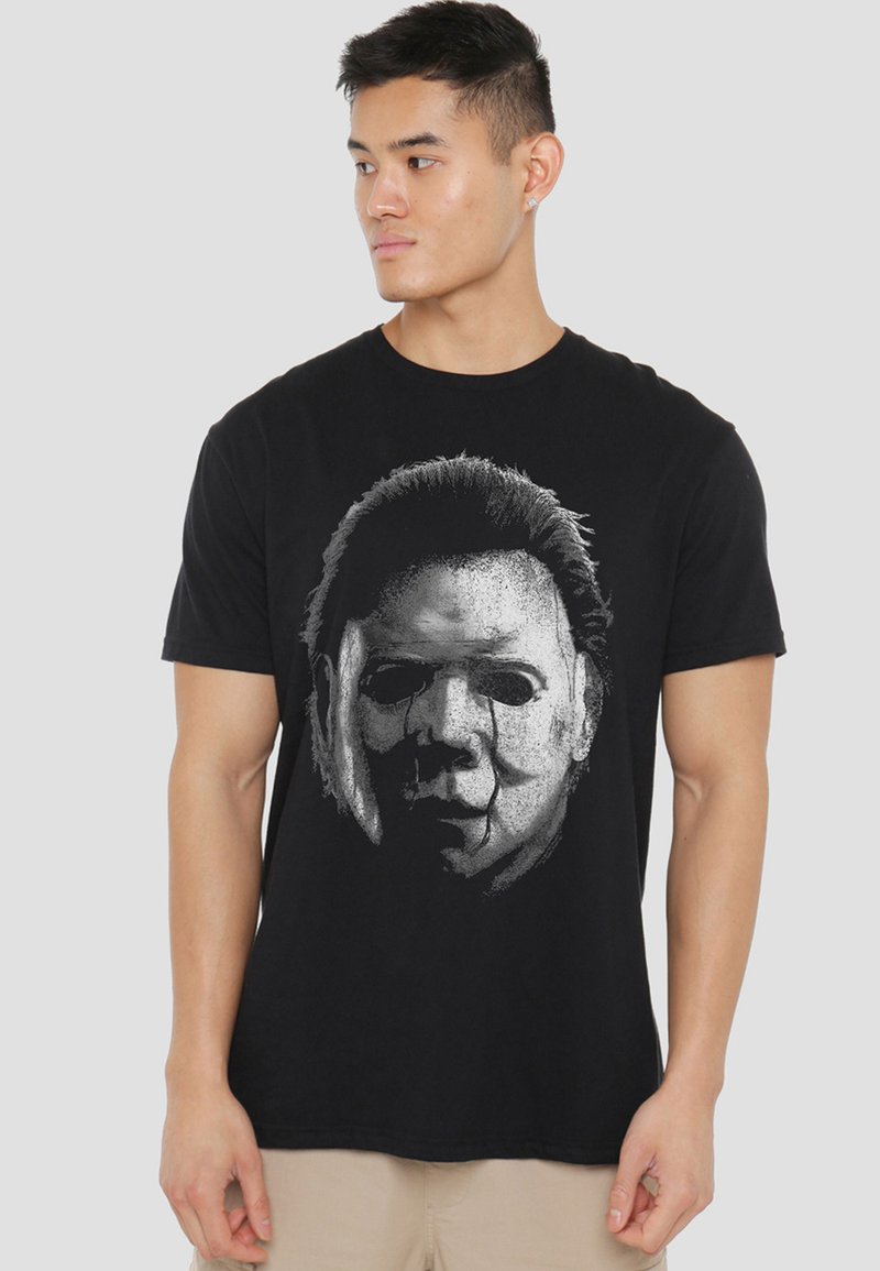 Black cotton t-shirt featuring a graphic print of a mask in white and gray, with detailed facial features and dark hair accents.