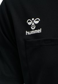 Sort trøje med Hummel-logo i hvid. Omfatter en lille brystlomme, korte ærmer og en glat tekstur.