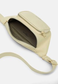 Kremowa torba crossbody o gładkiej fakturze, z zapięciem na zamek błyskawiczny i pojedynczym regulowanym paskiem. Wnętrze wyłożone ciemnym materiałem.