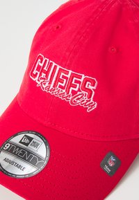 Cappellino da baseball rosso con ricamo bianco "CHIEFS Kansas City" sulla parte anteriore. Presenta una fascetta regolabile e un logo New Era sul lato.
