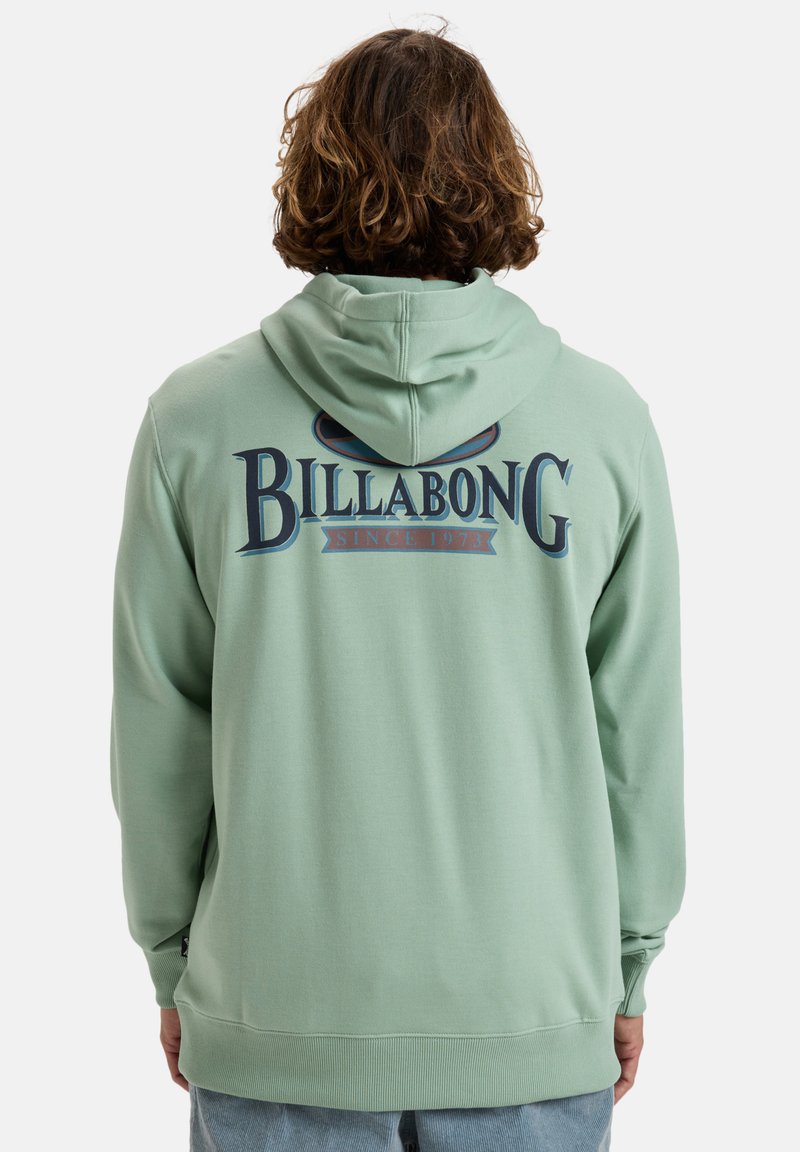 Sudadera verde claro con capucha ajustable, que presenta un gran logo de Billabong en la parte posterior en azul marino y rojo. Fabricada en una tela suave, de corte relajado.