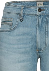 Light blue denim jeans featuring a zip-fly, five pockets, and contrast stitching. Includes a loop for a belt or accessory.