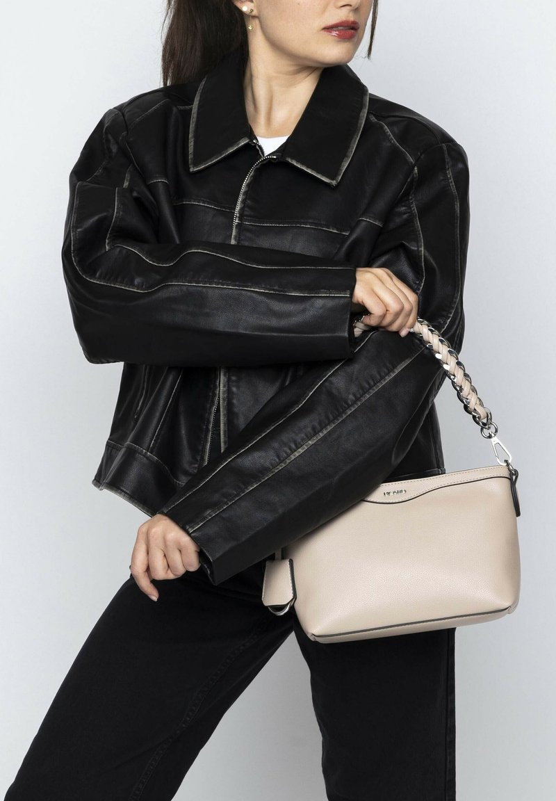 Black leather jacket with contrast stitching, paired with a small beige leather handbag featuring a braided strap and a zip closure.