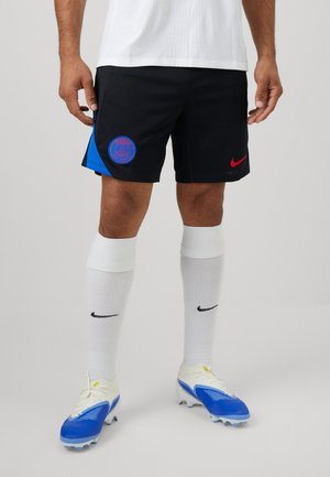 Svarte shorts med blå sidestykke og rødt Nike-logo, kombinert med hvite sokker og blå fotballstøvler med teksturert design.