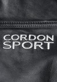 Schwarzes Leder mit auffälligem, weiß gesticktem Text "CORDON SPORT." Die Textur ist glatt und unterstreicht die Qualität des Materials.
