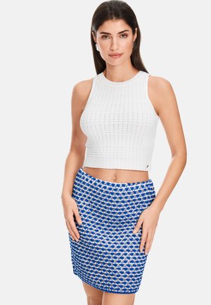 White knitted crop top with a textured pattern paired with a blue and white patterned skirt. Both pieces feature a fitted design.