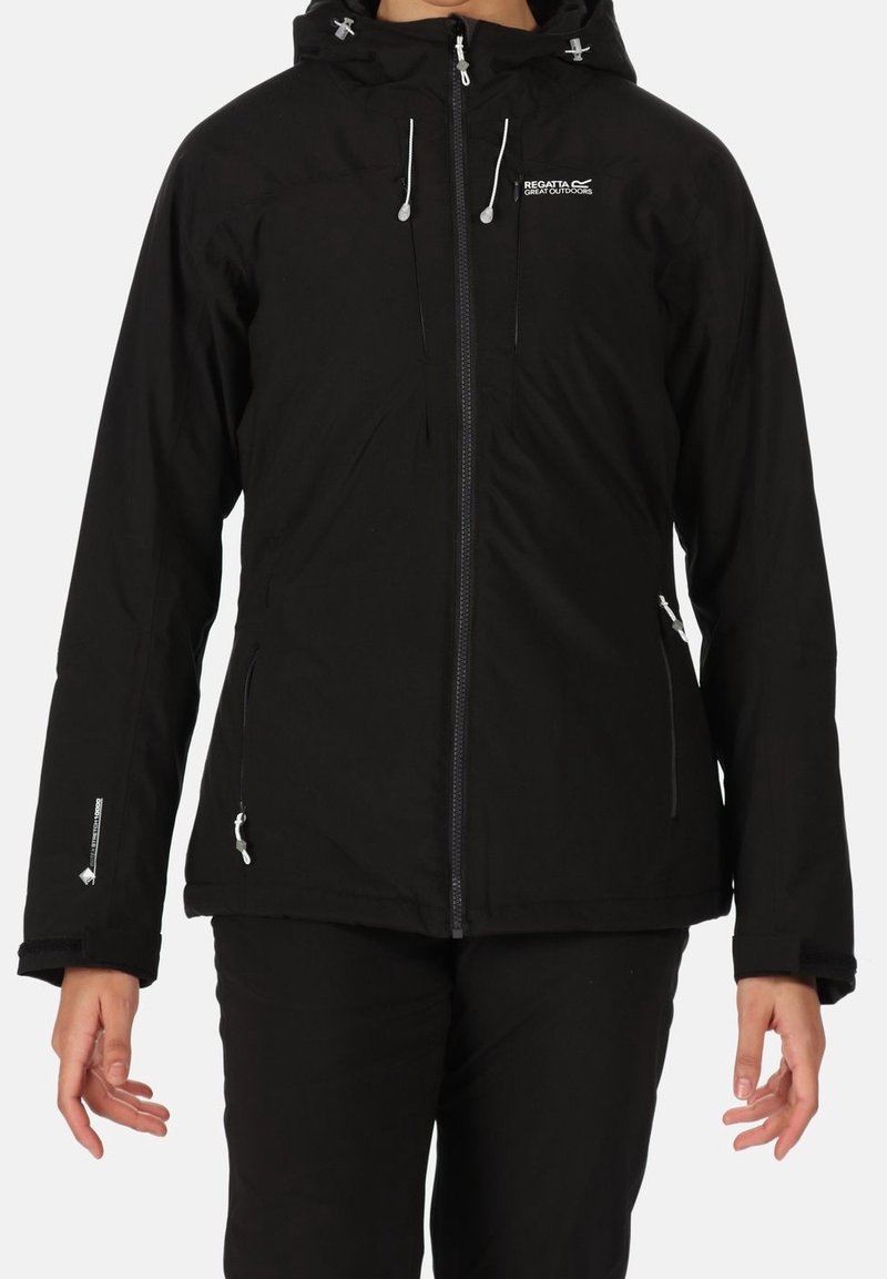Personne portant une veste noire à capuche Regatta Great Outdoors avec fermeture éclair à l'avant et poches latérales zippées, debout devant un fond uni.