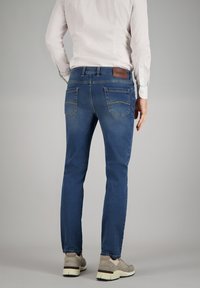 Herren Jeans aus blauen Denim mit schmaler Passform, Gesäßtaschen mit gestickten Akzenten und einem Leder-Brandpatch am Bund.