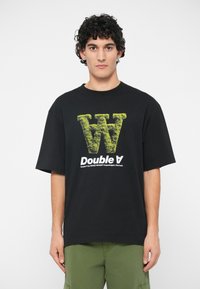 Črna bombažna majica s kratkimi rokavi, ki na sprednji strani nosi velik teksturiran zeleni logotip "W" in bel napis "Double A". Ohlapen kroj.