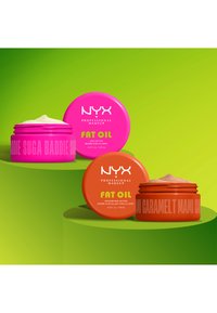 Two open NYX Fat Oil body butter jars, one bright pink labeled Suga Baddie, one orange labeled Caramel T Mami, on green curved surfaces.