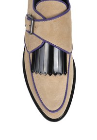 Beżowe zamszowe buty z czarnymi metalowymi detalami i purpurowymi akcentami, z szerokim paskiem z klamrą oraz szpiczastym noskiem.