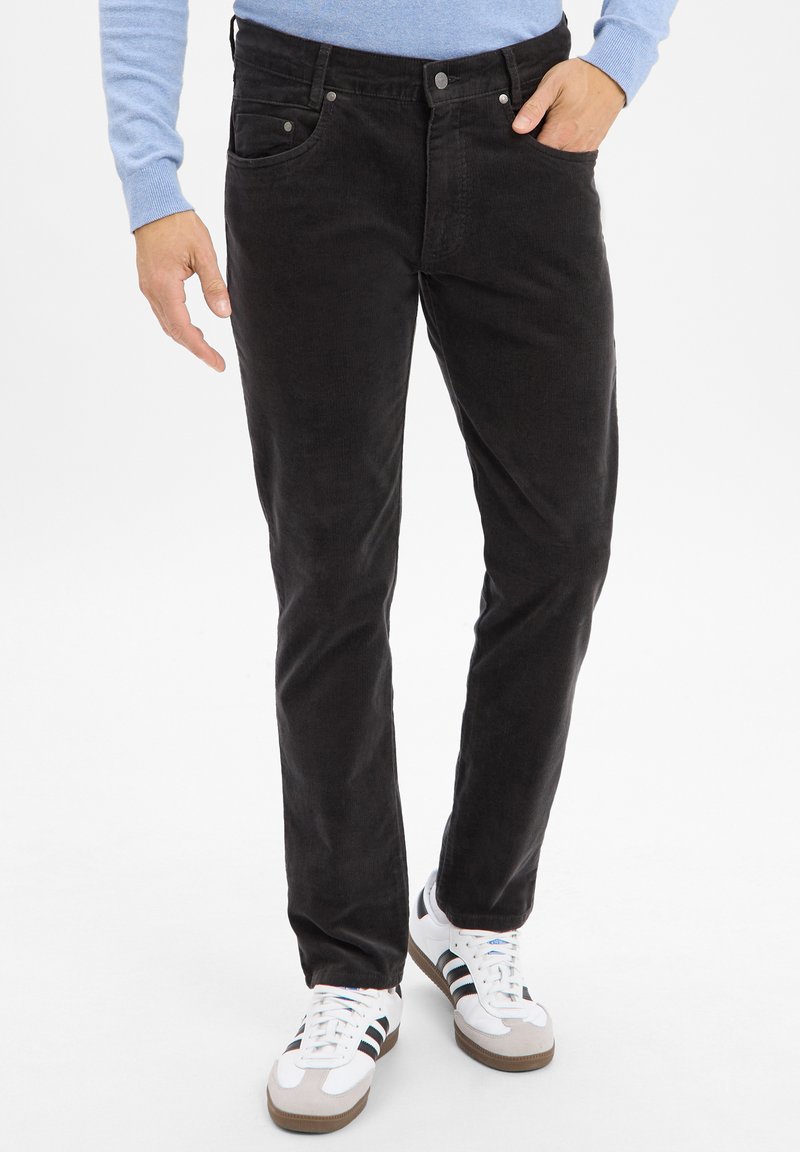 Black corduroy pants with a slim fit, featuring five pockets, silver hardware, and contrasting white athletic shoes.