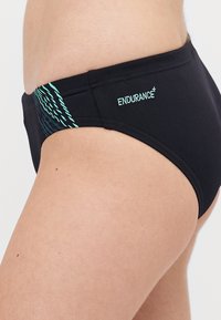 Černé plavecké slipy s tyrkysovým vzorem na bocích. Vyrobeno z hladkého, elastického materiálu. Obsahuje logo "ENDURANCE" v tyrkysové barvě.