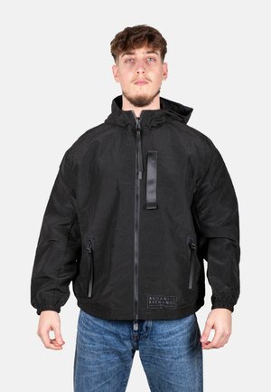 Giacca a vento nera con zip frontale, cappuccio, polsini elasticizzati e due tasche laterali. Il materiale ha una finitura testurizzata.