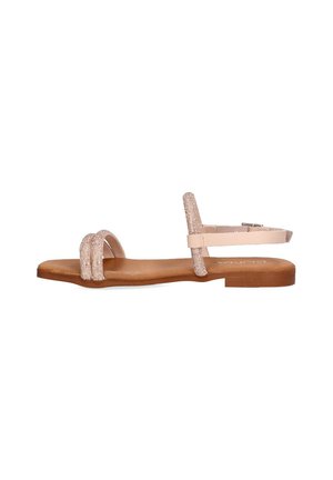Sandalia plana con tiras de color beige claro, una de las cuales presenta un detalle texturizado. Suela marrón con un diseño minimalista y correa ajustable en el tobillo.