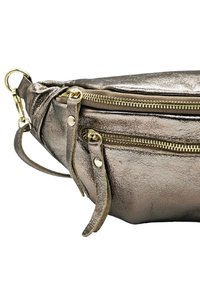 Sac en cuir argent métallique avec des fermetures éclair dorées, poches à double fermeture éclair, surface texturée et bandoulière détachable pour plus de polyvalence.