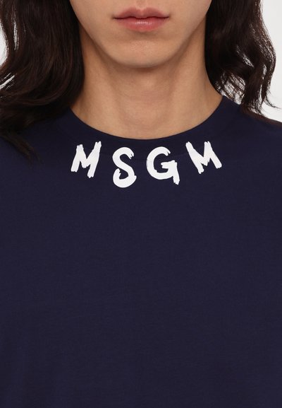 Tumesinane puuvillane T-särk, millel on rinnal julged valged trükitähed "MSGM", ümmargune kaelus ja pehme tekstuur.