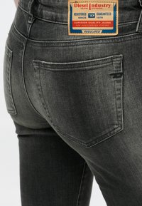 Tmavomodré rifle z denimu majú klasický dizajn s piatimi vreckami, výraznú značkovú nášivku na páse a jemnú vyblednutú textúru.