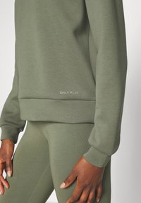 Olivově zelená mikina s dlouhými rukávy a žebrovanými manžetami, vyrobená z příjemného materiálu, s vyšitým logem "ONLY PLAY" na spodním lemu.