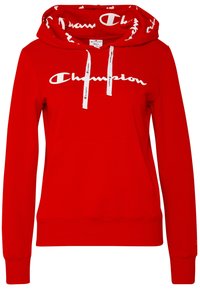Czerwony bawełniany hoodie z białym logo "Champion", białymi sznurkami z brandingiem oraz kieszenią typu kangur na przodzie. Długie rękawy z ściągaczami.