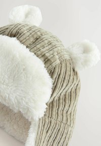 Chapeau en velours côtelé gris avec doublure en fausse fourrure blanche, doté d'oreilles arrondies et de rayures verticales texturées à l'extérieur.