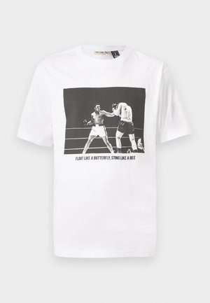 T-shirt blanc en coton avec un graphique en noir et blanc de deux boxeurs et le texte "FLAIRE COMME UN PAPILLON, PIQUE COMME UNE ABEILLE."