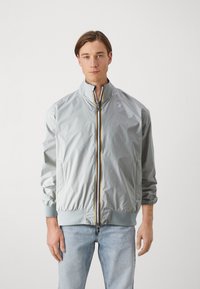 Giacca bomber leggera grigia con colletto alto, zip frontale con accento giallo, polsini elastici e design slim fit.