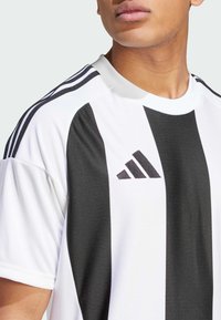 Wit en zwart gestreept sportshirt met een ronde hals, gemaakt van een gestructureerde stof, met het Adidas-logo op de borst en schouderstrepen.